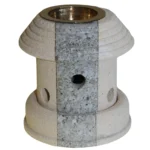 En olielanterne i metal præsenteres med en mat, sort overflade, der giver et rustikt udtryk. Lanterneformen er cylindrisk med en glasindsats, der har en klar, gennemsigtig struktur. Øverst findes en lille, rund ventilationsåbning, og i bunden er der en skruelåg, der muliggør påfyldning af olie. Håndtaget er lavet af metal og er buet for nem transport.