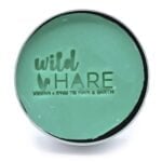 Fast shampoo i en rund, flad form, vejer 60 gram. Overfladen er glat med en let glans, og farven er en lys, grønlig tone. En tekstur af små, fine luftbobler kan ses. Der er en tydelig indgravering med teksten "Wild Hare" og "Aloe Vera" på overfladen, hvilket tilføjer et dekorativt element.