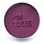 En rund, kompakt shampoo-bar med en dyb kirsebærfarve pryder overfladen. Den glatte tekstur er ensartet, uden synlige urenheder. Baren har en let glinsende finish, der reflekterer lys. På den ene side ses indgraverede bogstaver, der danner ordet "shampoo". Størrelsen er passende til håndholdt brug, og den vejer 60 gram.