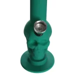 En miniatyr bong i grøn silikone med en skull-formet struktur. Overfladen er glat med en mat finish, der giver en blød tekstur. Der er en gennemsigtig perkolator og en lille, rund skål i metal. Bongen har en buet hals og en bred bund, hvilket giver stabilitet. Det samlede design er kompakt og moderne.