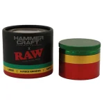 En runde, farverig krydderkværn med en diameter på 60 mm præsenterer sig i et rasta-inspireret design. Den øverste del er grøn, midten gul og bunden rød. Kværnen har små, skarpe tænder indeni, der er synlige gennem et gennemsigtigt vindue. Overfladen er glat med en mat finish, og der er en metalknap til at åbne kværnen.