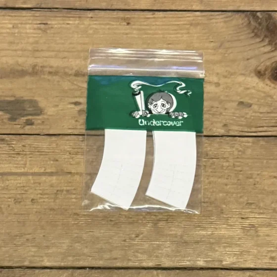 Grønne filtertips præsenteres i en pakke med en mat overflade, der har en subtil glans. Hver filtertip er rektangulær med afrundede hjørner og viser en let struktureret tekstur. Farven er ensartet grøn med en lysere nuance langs kanterne. Pakken er lukket med en simpel, hvid label, der indeholder minimal tekst og grafiske elementer.