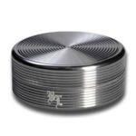 En sort krydderikværn med en bølget overflade præsenterer sig med en diameter på 50 mm. Den har en glat, mat finish, der kontrasterer med det blanke, metalagtige indre. Kværnen er opdelt i to sektioner, som kan adskilles. På toppen findes en lille, rund knap til at dreje, mens der er små, prikkede mønstre langs kanten.