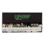 Euphoria Mystical King Size Slim er en lang, slank rulle med en glat overflade i en dyb mørk farve. Det indviklede mønster præsenterer subtile, bølgende linjer i lyse nuancer af lilla og guld, der skaber en mystisk effekt. Rullen er fastgjort med en tydelig perforering, der giver mulighed for nem adskillelse. Materialet har en let glans, der reflekterer lys.