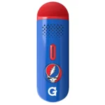 En bærbar vaporizer præsenteres med en slank, sort krop og en glat overflade. Den har en minimalistisk, oval form med afrundede kanter. Fronten prydes af et farverigt, detaljeret logo, som inkluderer et kranium og blomster. En lille, cirkulær knap er placeret på siden, og der er et gennemsigtigt vindue, der viser indholdet.