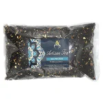 Sort te i en 1 kg pose dominerer beskrivelsen, med en mat overflade og en enkel, minimalistisk design. Posen har et tydeligt, hvidt label med sort tekst, der angiver navnet på teen, "Black Magic Blend". Omgivet af en subtil geometrisk baggrund, fremstår posen stilren og moderne. Kanten er forseglede, og materialet giver en let struktur.