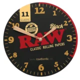 En rund vægure med en diameter på 30 cm præsenterer sig i en mat sort finish. Urskiven er enkel og uden tal, kun markeret med streger ved hver time. Viseren er slank og i en kontrasterende sølvfarve, hvilket giver en klar synlighed. Urkassen er lavet af metal, og det minimalistiske design fremhæver et moderne udtryk.
