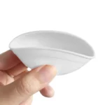 En lille skål med en diameter på 7 cm i hvid silicone med rosa detaljer. Skålens overflade har en glat og blød tekstur, der er let at rengøre. Den rosa kant giver en kontrast til den hvide bund, og skålen har en rund form med en let buet kant. Den fleksible struktur muliggør nem håndtering.
