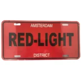 Et metal skilt præsenterer sig med en rød baggrund og hvid tekst, der angiver "Red Light District". Bogstaverne er i en tydelig, sans-serif skrifttype, som står i kontrast til den intense farve. Kanterne er lige og skarpe, og overfladen har en let glans, der skaber en subtil refleksion. Skiltet har en robust, industrielt udseende finish.