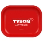 En firkantet, grå betonplade præsenterer sig med en ru overflade, som indeholder små, tilfældige lysere og mørkere nuancer. Pladen måler 180 x 140 mm og har afrundede kanter, hvilket giver et blødt udtryk. Overfladen er mat og ensartet, uden synlige mønstre eller teksturer, hvilket understreger det minimalistiske design.