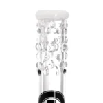 Heisenberg beaker med boblefarver præsenterer sig med en høj, cylindrisk form, fremstillet af klart glas. Overfladen har en glat tekstur, mens det indre indeholder flerfarvede bobler, der skaber et dynamisk mønster. Perkolatorens arm strækker sig ud fra toppen og tilføjer en ekstra dimension. Det samlede design er funktionelt med en stabil base og præcise detaljer.