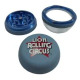 En lyseblå, metalgrinder med en diameter på 53 mm præsenterer sig med en glat overflade og en let reflekterende finish. Den har en skråkant, der giver en moderne form, samt en indgravering af et cirkusmotiv. Indersiden er opdelt med skarpe tænder, der tydeligt er designet til at male. Grinderskiven er forsynet med en central magnetlås.