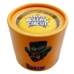 En rund krydderikværn med en diameter på 53 mm, fremstillet af orange glas og metal. Overfladen har en glat, skinnende tekstur, og der er en tydelig gribe kant langs kanten. Kværnen har en metalmekanisme, som er synlig gennem glasset. Der er små, indgraverede detaljer i metallet, der tilføjer et dekorativt element.