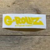 Logoet præsenterer sig i en lys gul farve med sort tekst. Det består af ordet "G-Rollz" i en moderne, sans-serif skrifttype, hvor bogstaverne er let afrundede. Baggrunden er ensfarvet, uden mønstre eller dekorationer, hvilket giver en ren og minimalistisk fremtoning. Logoets design er enkelt og letlæseligt, hvilket fremhæver navnets karakter.