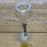 En skål i klart glas med en rund form og en glat overflade. Skålen har en diameter på cirka 20 cm og en dybde på 5 cm. Den prydes af slidsede detaljer, der giver en interessant tekstur. Kanten er let buet og skaber en elegant profil. Indvendigt reflekteres lys, hvilket fremhæver de klare linjer og skarpe kanter.