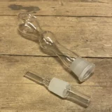 Glaspibe med et klart og gennemsigtigt design, der strækker sig 18 cm i længden. Den har en elegant, buet form og et bredt mundstykke, der giver en glat overflade. Overfladen er glat med en let reflekterende effekt. Piben er prydet med subtile detaljer, der fremhæver det håndværksmæssige aspekt. Farven er krystalren, hvilket giver et minimalistisk udtryk.