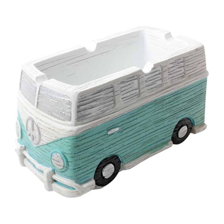 Et askebæger i form af en klassisk Volkswagen bus præsenterer sig med en lys blå farve og detaljerede sorte og hvide linjer. Bægeret har afrundede kanter og en skinnende, glat overflade. Indvendigt er der en lille hældning, der leder til et centralt rum til aske. Bunden er flad og stabil, hvilket sikrer, at det står sikkert.