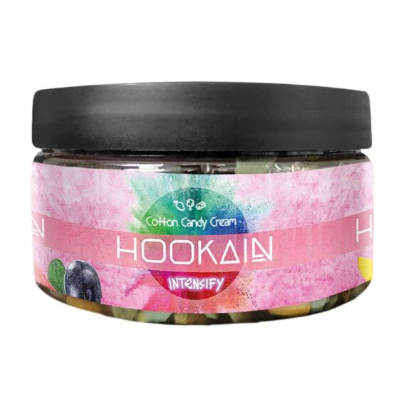 En rund beholder i hvid plast med en skruehætte prydet med et farverigt design, der inkluderer nuancer af lyserød, blå og lilla. Labelen viser et grafisk mønster og teksten "Cotton Candy Cream", fremhævet i en letlæselig skrifttype. Beholderens indhold er en lyserød, let fluffy substans, der skaber et visuelt indtryk af sødme og lethed.