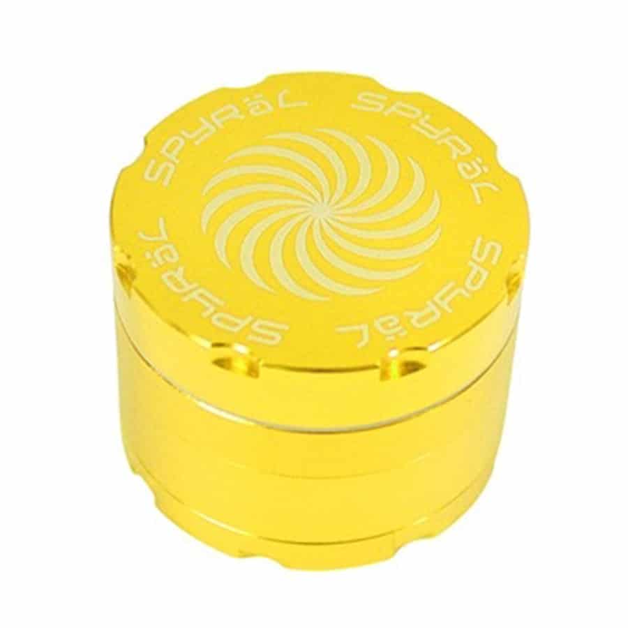 En gylden krydderigrinder med fire lag præsenterer sig med en glat, metallisk overflade. Grinderens øverste del har et skruelåg, mens den nederste del indeholder et fint sigte. De fire lag er adskilt af skarpe tænder, der er designet til effektiv nedbrydning. Mønstret på overfladen giver en elegant, strukturret effekt.