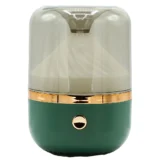 En aroma diffuser præsenterer sig i en kombination af grønne og bronzefarvede nuancer. Den har en rund, glat form med en mat overflade og en let struktur. Øverst er der en åbning med en diskret, rund knap. Diffuseren har en belysningseffekt, der skaber en blød glød, og dens bund er stabil og flad.