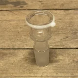 En skulpturel bong med en hvid ring i midten, der skaber en kontrast til den mørke, glatte overflade. Formen er slank og buet, med en rund top og en bredere bund. Materialet fremstår klart og glasagtigt. Der er synlige luftbobler i glasset, der tilføjer karakter. Den har en tilpasset mundstykke, som er let afrundet.