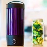 En moderne el-kedel i rustfrit stål præsenterer en glat, poleret overflade med en kromfinish. Kedlen har en buet form og en sort plastik håndtag, der sikrer et sikkert greb. På forsiden findes en digital temperaturdisplay med klart, hvidt skrift. Den afrundede tud er designet til præcis hældning, og bunden har en cirkulær, sort sokkel.