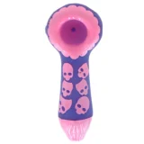 Et dekorativt skull af et sort får med en glat overflade, prydet med detaljerede ansigtstræk og horn, der buer opad. Skallen er placeret på en lys pink base, som tilføjer kontrast til den mørke farve. Materialet fremstår som keramik, og overfladen har en let glans. Skulpturen er kompakt og har en moderne æstetik.
