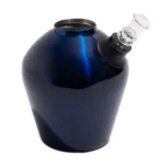 En blå, glansfuld bong i rustfrit stål måler 33 cm i højden. Den har en slank, cylindrisk form med en bredere bund, der giver stabilitet. Overfladen reflekterer lys, hvilket skaber en skinnende effekt. En udskæringsdetalje fungerer som greb, og der er en indsat til et vandkammer, der sikrer filtrering af røg.