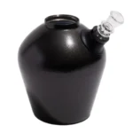 En sort, glinsende bong i rustfrit stål pryder midten af beskrivelsen. Den har en slank, cylindrisk form med en bred base og en smal hals. Overfladen har en spejlrefleksion, der skaber et elegant udtryk. En lille perkolator er placeret inde i bongens krop, og der er en stål- eller glasadapter til indføring af røg.