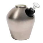 En bongs struktur er fremstillet af rustfrit stål med en glansfuld, spejlreflekterende overflade. Den er 33 cm høj med en slank, cylindrisk form, der har en bredere base for stabilitet. En krum hals strækker sig opad, og en sidemonteret skål med perforeringer er synlig. Det minimalistiske design har ingen synlige knapper eller symboler.