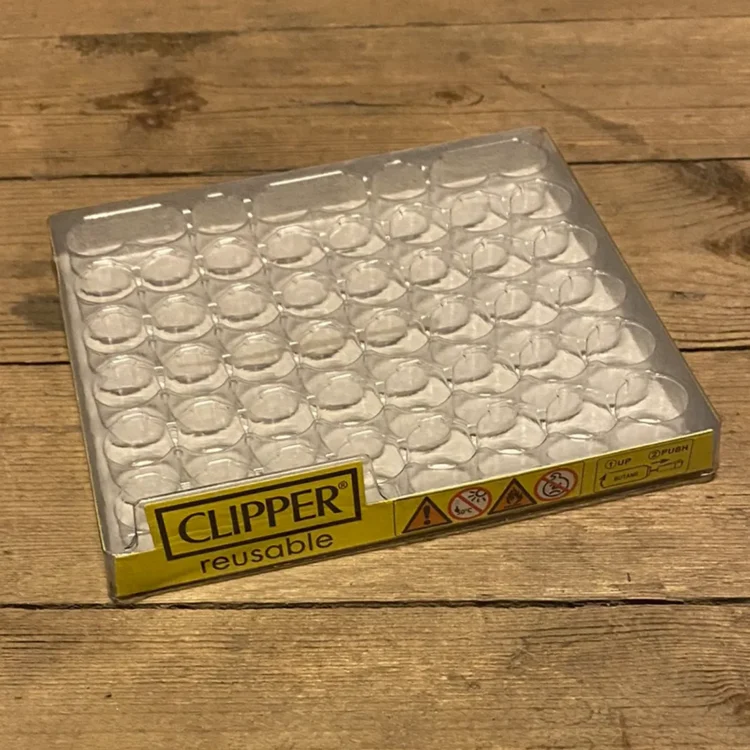 En displaypakke indeholder 48 klipslightere i forskellige farver og mønstre. Lighterne er slanke og har en glat plastikoverflade. Farverne spænder fra lys blå, grøn og rød til mørkere nuancer. Hver lighter har en sort flammejustering og et logo på forsiden. Displayet er organiseret i rækker med let tilgængelige lightere.