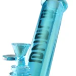 En 30 cm høj bong i klart glas præsenterer sig med en dyb blå farve på gear-delen. Den har en slank, cylindrisk form med afrundede kanter og en bred base for stabilitet. Der er en indbygget perkolator, og røret har en glat overflade. En multifunktionel skål med en lille håndtag er synlig, der bidrager til det samlede design.