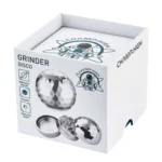 En cylindrisk grinder med en diameter på 65 mm, fremstillet af metal med en glat overflade, der reflekterer lys. Den har en sølvfarvet finish med en detaljeret, indgraveret logo øverst. Den øverste del har en skruelåg med små, tandede kanter for nem åbning. Indvendigt ses skarpe tænder, der er designet til at male materialer effektivt.