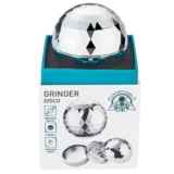 En metalgrinder med en diameter på 65 mm, prydet med en skinnende overflade i sølvfarve. Grinderens krop har en glat, poleret tekstur, mens toppen har et indgraveret mønster med små huller til knusning. Knivene indeni er skarpe og vinklede, hvilket sikrer effektiv malning. Den har en skridsikker kant for bedre greb og en lille magnetisk lukning.