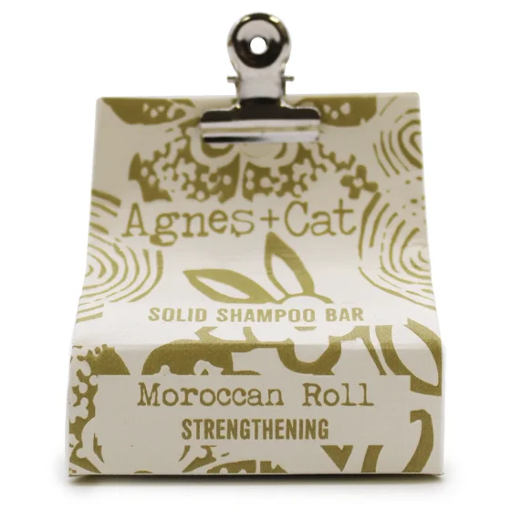 En solid shampoo bar præsenteres i en oval form med en glat, blød overflade. Farven er en varm, gylden beige nuance, der giver en naturlig fornemmelse. Overfladen har en let glans, mens der er indgraveret tekst, som angiver produktets navn. Den kompakte størrelse gør den let at håndtere, og den fremstår som en miljøvenlig alternativ til flydende shampoo.