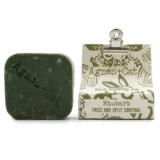 En solid shampoo bar præsenterer sig i en oval form med en glat overflade. Farven er en dyb, varm rabarbernuance, der strækker sig fra lysere til mørkere toner. Strukturen er kompakt og ensartet uden synlige urenheder. Der er en let glans, som indikerer en fugtig tekstur, og baren har ingen synlige emballager eller etiketter.