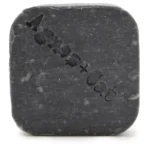 En fast shampoo-bar præsenteres i en rund form med en glat, matte overflade. Farven er en blød blanding af havgrøn og lys mosgrøn. Baren har en let struktureret overflade med små, ujævne områder, der skaber en naturlig effekt. Ingen synlige mærker eller etiketter pryder overfladen, hvilket giver et enkelt og minimalistisk udtryk.