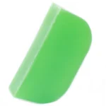 En solid shampoo-bar præsenteres med en oval form og en glat overflade. Farven er en lys, sart grøn med subtile nuancer af grå. Teksten er trykt i sort og angiver produktets navn og ingredienser. Baren er pakket ind i et simpelt, naturfarvet papir med en mat finish, der fremhæver det organiske udtryk.