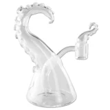En klar olie-bong med en højde på 17 cm præsenterer sig med en glat, gennemsigtig overflade og organiserede, tentakelformede udvidelser, der strækker sig fra kroppen. Bongens form er kurvet, hvilket giver en organisk æstetik. Mundstykket er let udvidet, og bunden er bred for stabilitet. Det samlede design fremhæver en minimalistisk, men samtidig kunstnerisk tilgang til glasarbejde.