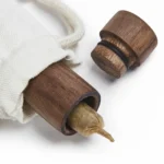 Granny's Weed premium træjoint-hylster har en slank, cylinderformet struktur med en længde på 140 mm. Den er fremstillet af lyst træ med en glat overflade, der fremhæver den naturlige kornstruktur. Hylsteret har en åben ende og en lukket ende, samt en subtil, mørkere farvetone langs kanten. Mønsteret er enkelt og elegant, uden yderligere dekorationer.