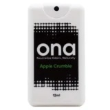 En lille, cylindrisk sprayflaske med en transparent, mat overflade. Flasken har en hvid spraydyse med en sort knap, der muliggør dosering. Etiketdesign i bløde farver præsenterer navnet "Apple Crumble" i tydelig, sort skrift. Baggrunden er hvid, hvilket fremhæver flaskens enkle, stilrene udtryk og de lette, frugtagtige nuancer på etiketten.