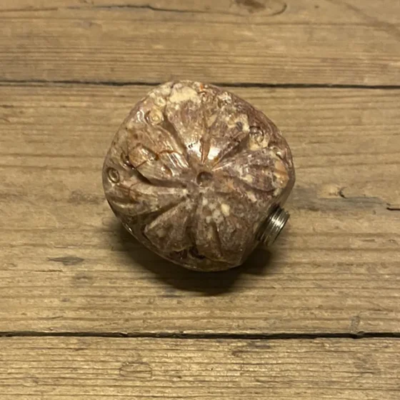 Et rundt pibehoved fremstår med en glat, grå stenoverflade, der har fine, naturlige åretegninger. Den metalliske gevindforbindelse er sølvfarvet og skinner let i lyset. Pibehovedet har en afrundet form med en let udspringende kant, mens den underside er flad og ensartet. Sammenføjningen mellem sten og metal er præcist udført.