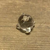 En rund glasrist med en diameter på 12 mm, præget af en glat, hvid overflade, der reflekterer lys. Risten har et minimalistisk design med små perforeringer, der skaber et diskret mønster. Kanten er let afrundet, hvilket giver et blødt udtryk. Materialet fremstår robust og holdbart, velegnet til en moderne indretning.