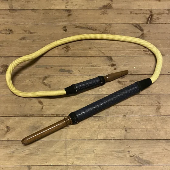 Traditionel tyrkisk slange i en strømlinet form med en glat, skinnende overflade. Den har et sort læderhåndtag, som er elegant og strukturelt robust. Mønsteret på slangen er detaljeret med fine linjer og ornamenter, der tilføjer et kunstnerisk præg. Farverne er varme og jordnære, hvilket fremhæver den håndlavede kvalitet.
