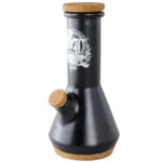 En sort bong i glas med en højde på 23 cm præsenterer sig med en slank, cylindrisk form. Den har en bred, stabil bund og en smal hals, der afsluttes med en afrundet kant. Overfladen er glat med en blank finish, der skaber refleksioner. En grøn, bladformet detalje dekorerer siden, hvilket giver et unikt præg.