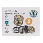 En sølvgrå grinder med en blank, metallisk overflade prydet med et detaljeret, indgraveret bitcoin-symbol. Grinderens struktur omfatter en topdel med skarpe tænder til formaling, mens midterdelen har små huller til at slippe det malede materiale gennem. Den nederste del fungerer som opsamler, hvor det malede materiale samles. Kanten er let buet, hvilket giver en ergonomisk følelse.