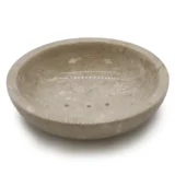 En oval skål i honningfarvet marmor præsenterer en glat og poleret overflade, der er præget af naturlige årer i nuancer af beige og lysbrun. Skålen har en let buet form, der giver et elegant udtryk. Kanterne er bløde og afrundede, hvilket fremhæver materialets unikke tekstur og naturlige skønhed. Marmorens glans tilføjer en subtil refleksion.
