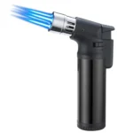 En sort lighter med en slank, ergonomisk form og en mat overflade. Den har en jetflammeudgang, der tydeligt er synlig foran. På siden ses en trykknap i sølvfarvet metal, som aktiverer flammen. Lighterens bund har en lille vinduesåbning, der viser niveauet af gas. Det samlede design er enkelt og funktionelt.