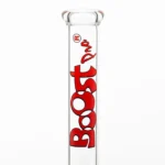 En høj, rød glasbeholder med en glat overflade og en cylindrisk form. Beholderens top er bredere end bunden, hvilket giver en stabil base. Den har en let skrå form mod toppen, der afsluttes med en lige kant. Indvendigt er der en blank finish, der reflekterer lys og skaber dybde. Beholderen har en kapacitet til at rumme væsker.