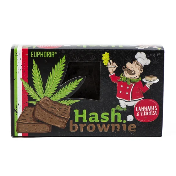 En mørkebrun brownie med en glat, skinnende overflade præsenterer sig med en let sprød skorpe og en blød, saftig indre. Toppingens tekstur er lidt ujævn, og der er små stykker af hakket nødder synlige. Kanter er let krummede, og der er en let glans, der indikerer fugtighed. Brownien er placeret på en lys, rustik træplade.